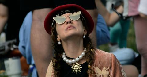 Woman looks at sky and waits for the eclipse to begin while wearing sunglasses