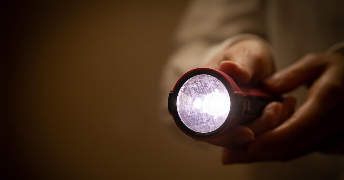 person holding flashlight in the dark.