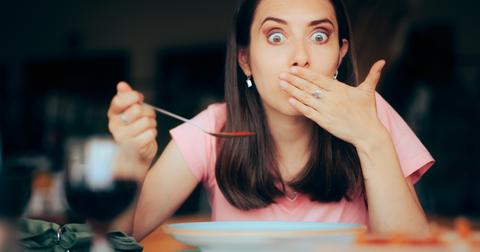 A woman becomes nauseated while consuming food in a restaurant.