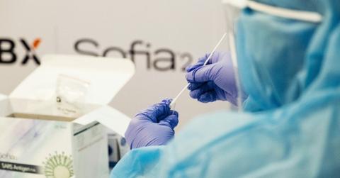 A person wearing PPE tests a sample