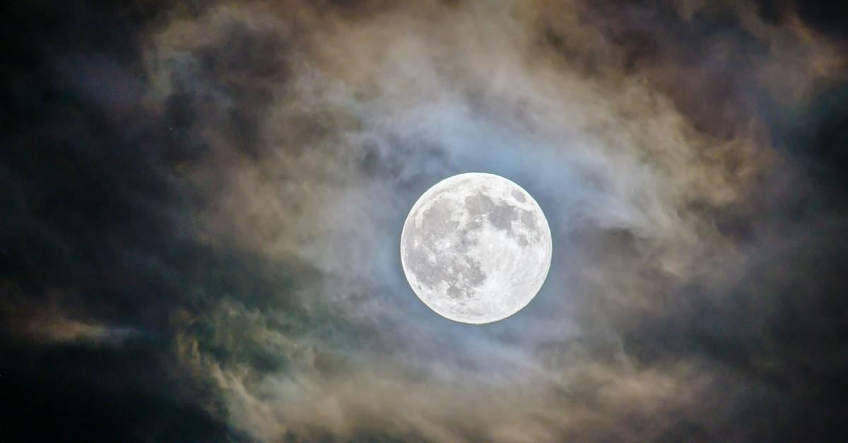 The moon glows large in a break in the clouds