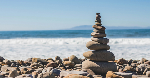 A pile of rocks appear stacked in front of the ocean