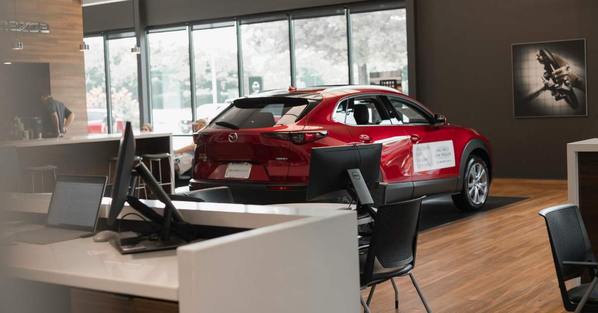 A red car is parked inside of a dealership office
