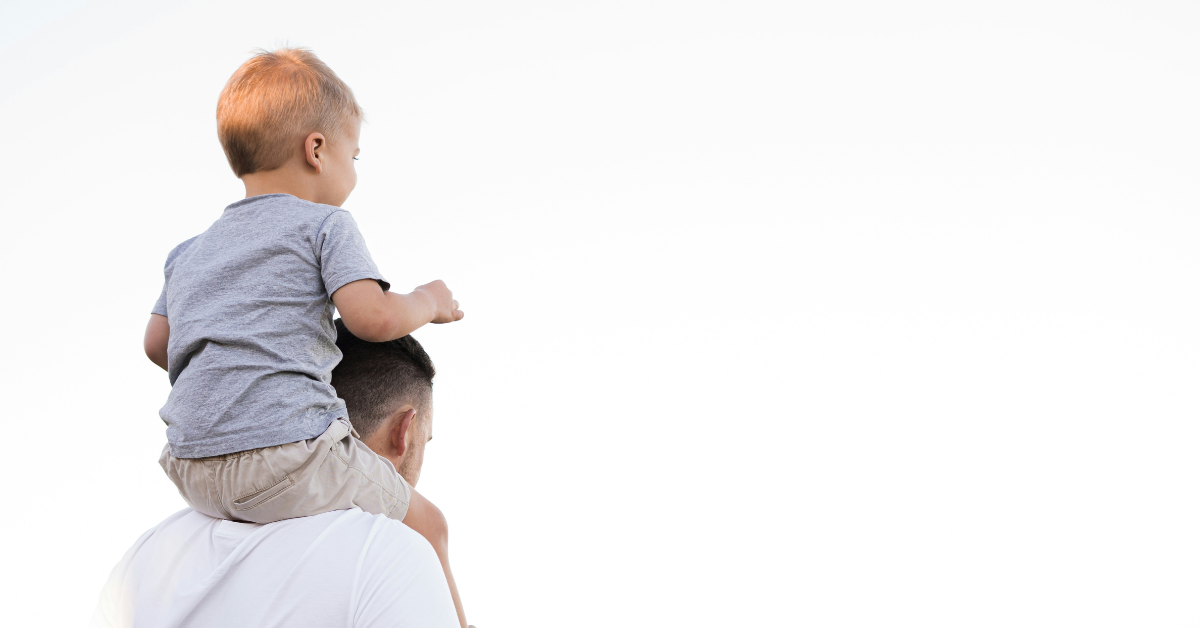 A man carries a young child on his shoulders