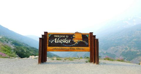 Welcome to Alaska sign stands on the edge of a mountain range