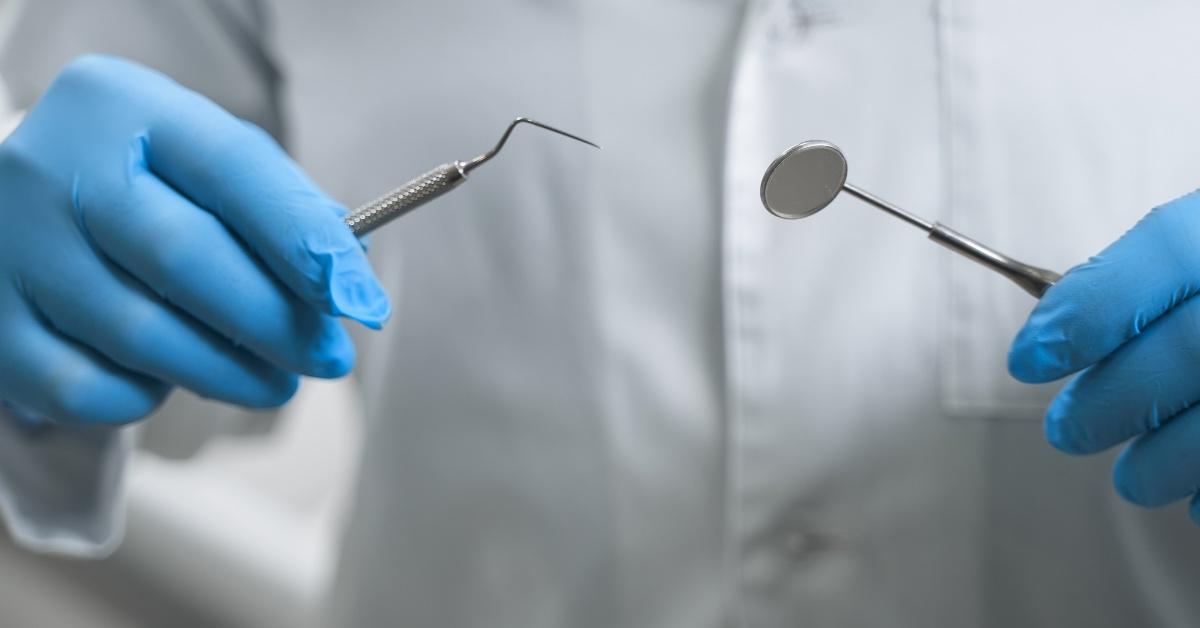 A dentist holds tools to work on a patient.