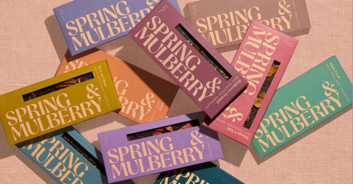 Spring & Mulberry bars are scattered across a pink backdrop 