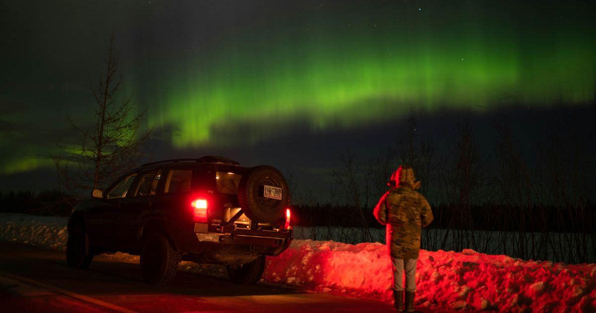 A man standing beside a car, looking at auroras in the sky. (Representative Cover Image Source: Pexels | John De Leon)