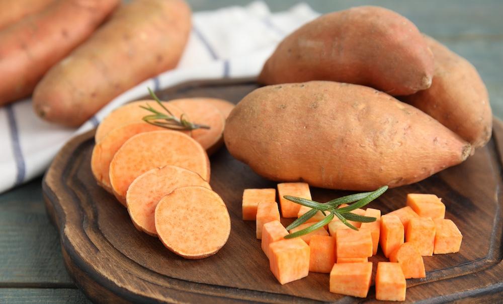 Sweet potatoes sliced and cubed on a wooden tray.