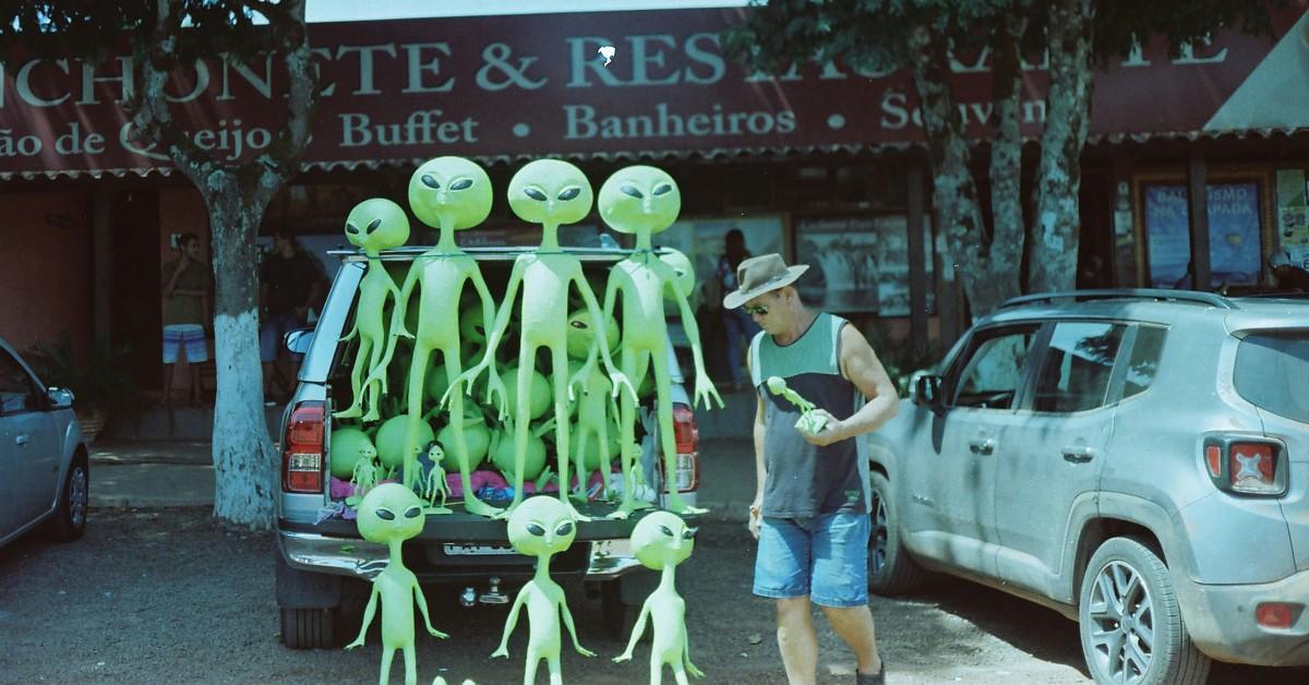 A man stops to inspect the green aliens for sale outside of a storefront 