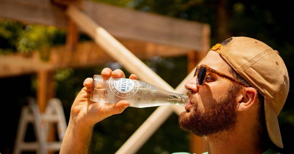 Man with sunglasses drinks from a bottle of sparkling water (Representative Cover Image Source: Unsplash | Conor Brown)