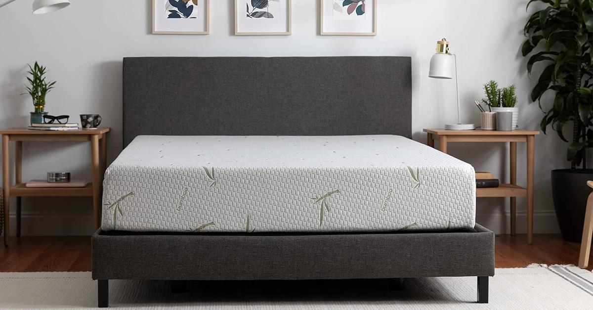 bare mattress in grey bed frame in bedroom with wooden nightstands.