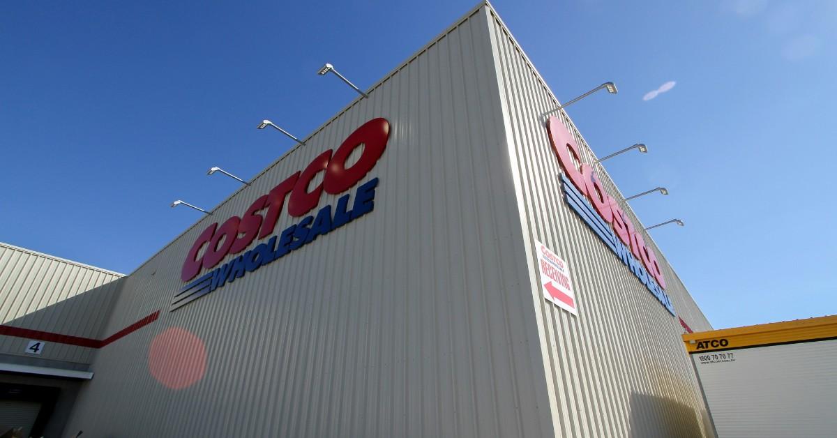 A Costco storefront sits against a bright blue sky