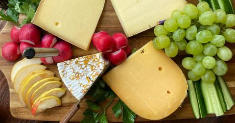 Various cheeses sit atop a cutting board