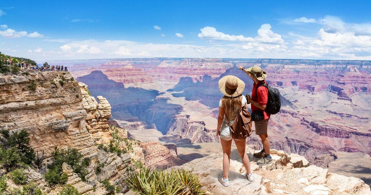 A couple on top of the mountain looking at the beautiful landscape of the South Rim of Grand Canyon National Park. (Representative Cover Image Source: Getty Images | MargaretW)