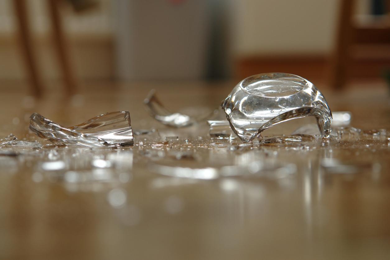 A glass bottle is pictured shattered on the floor.