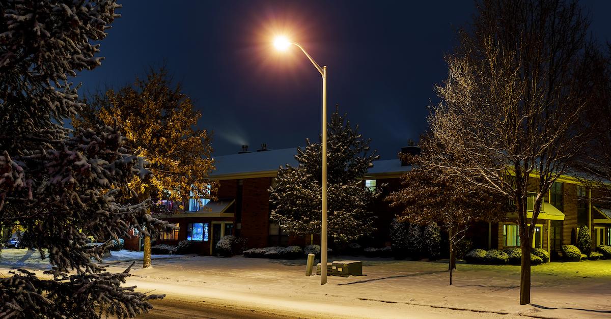 Streetlight illuminates quiet street with houses in snow