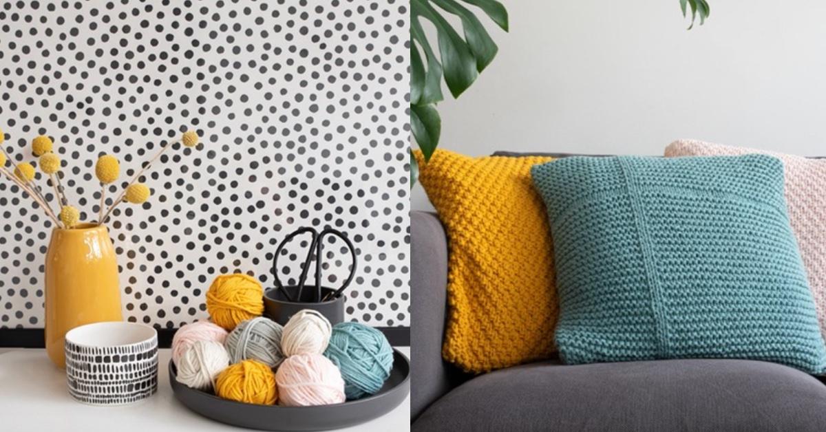 Pile of balls of yarn in pastel colors on a table; three pastel knit pillows on a grey couch