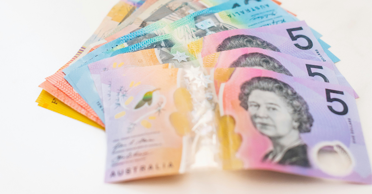 A collection of bills featuring Queen Elizabeth are fanned out on a table