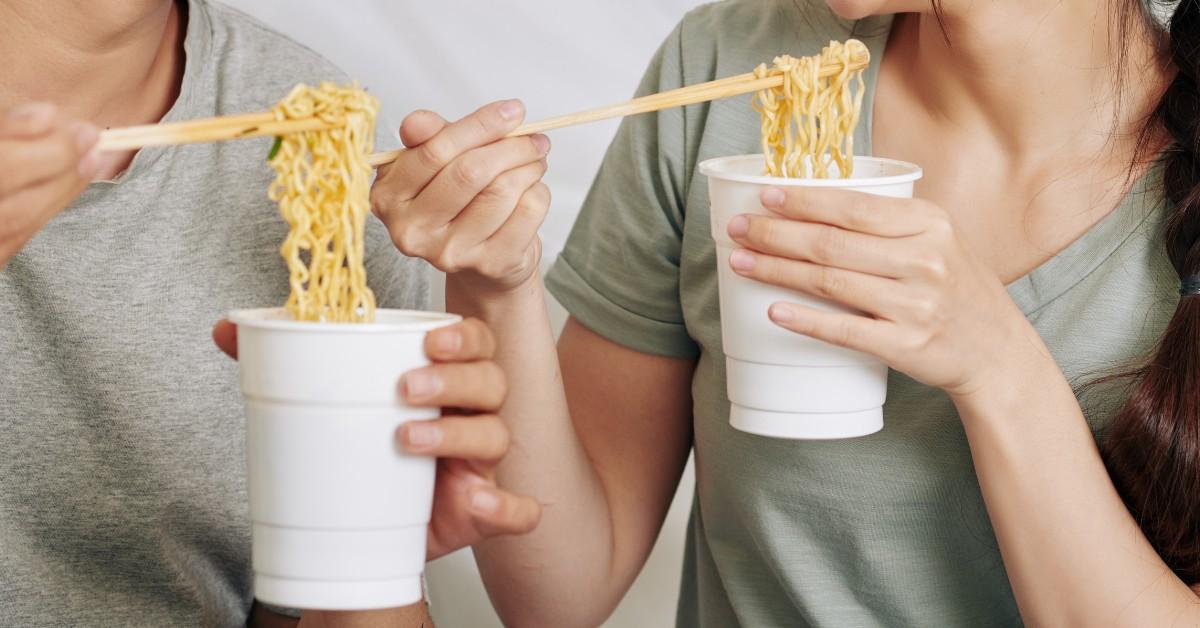 Close up of man and woman eating instant ramen noodles