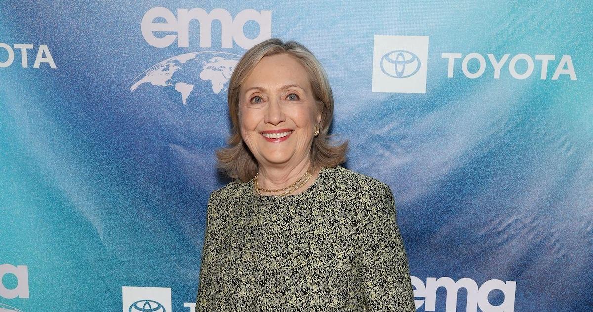 Hillary Clinton smiles in front of a blue backdrop at the EMA IMPACT Summit at the Pendry West Hollywood in Los Angeles in June 2024.