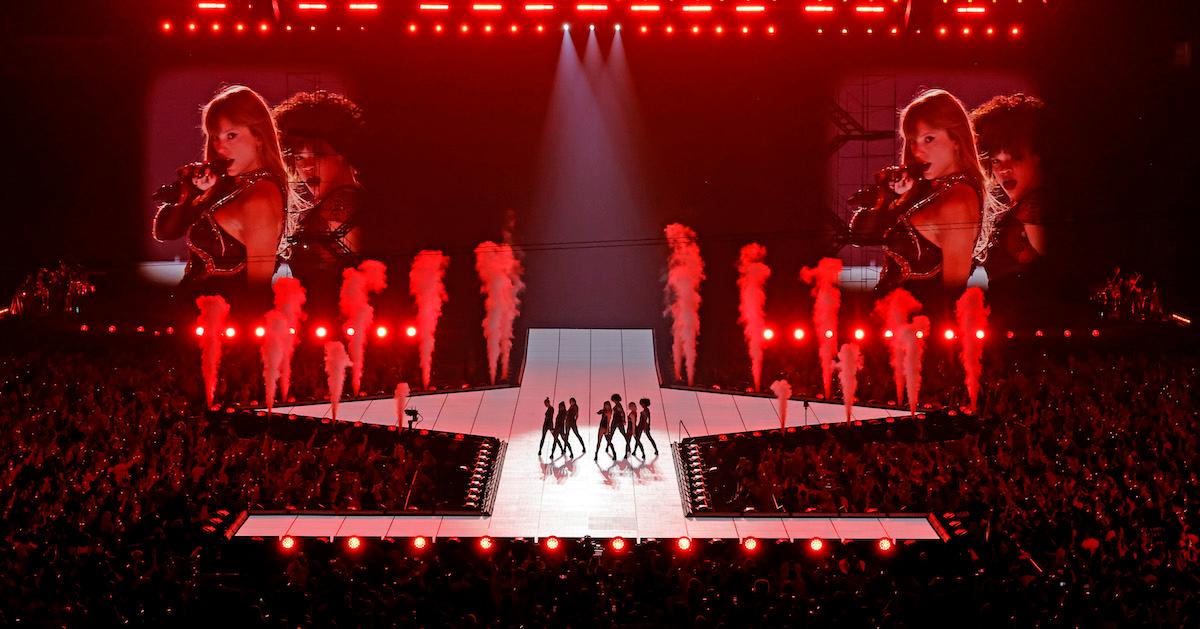 Taylor Swift and her dancers perform on stage, with the floor crowd shown around the stage.