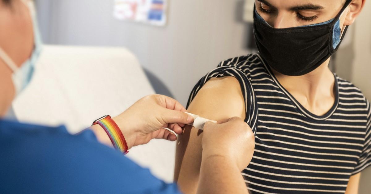 A medical provider places a band aid on a patient after administering a vaccine 