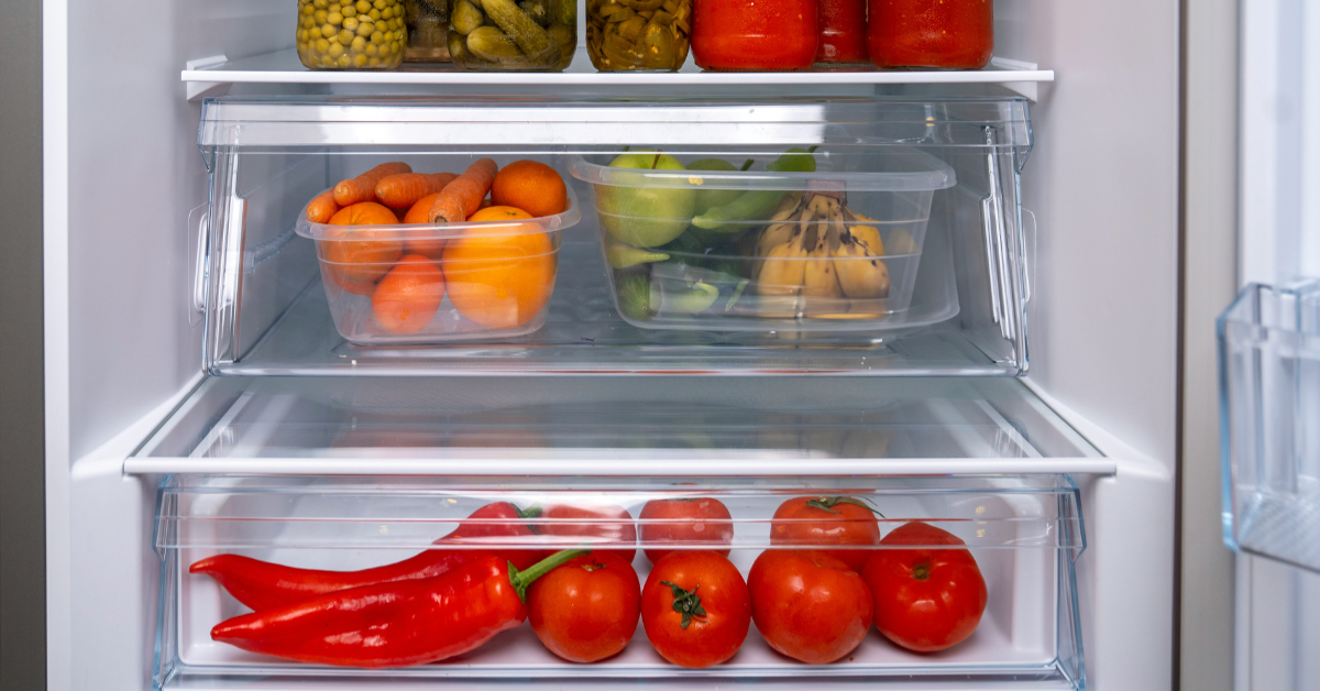 An open refrigerator shows food in the crisper drawer