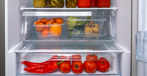 An open refrigerator shows food in the crisper drawer