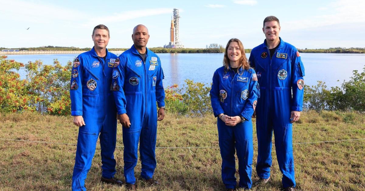 Astronauts stand in front of the Artemis II rocket