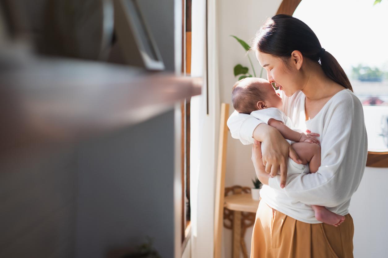 Mom holding baby next to a sunny window