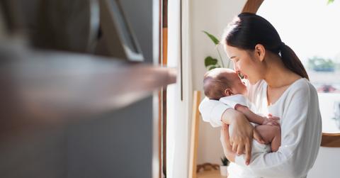 Mom holding baby next to a sunny window