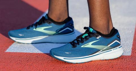 Product photo of the Brooks Ghost 15 running shoes on a pair of feet standing on a track