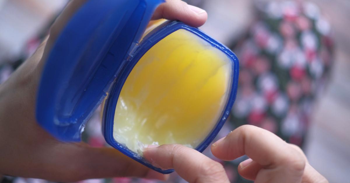 Close-up photo of a finger digging into an open container of Vaseline