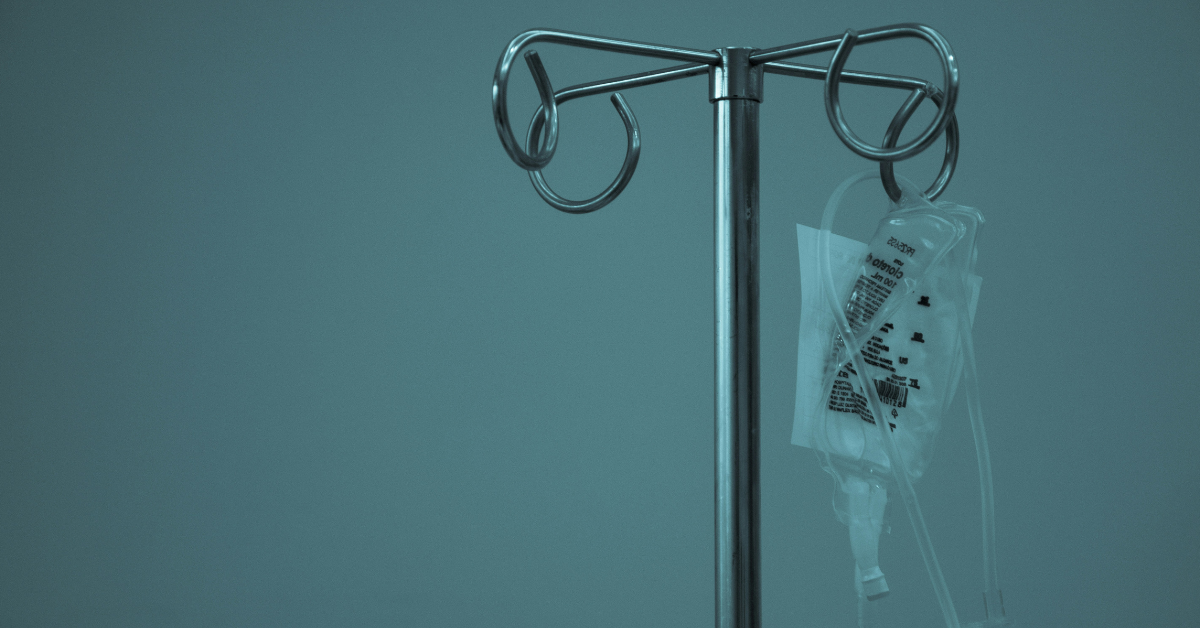 An IV bag hangs from a metal pole 