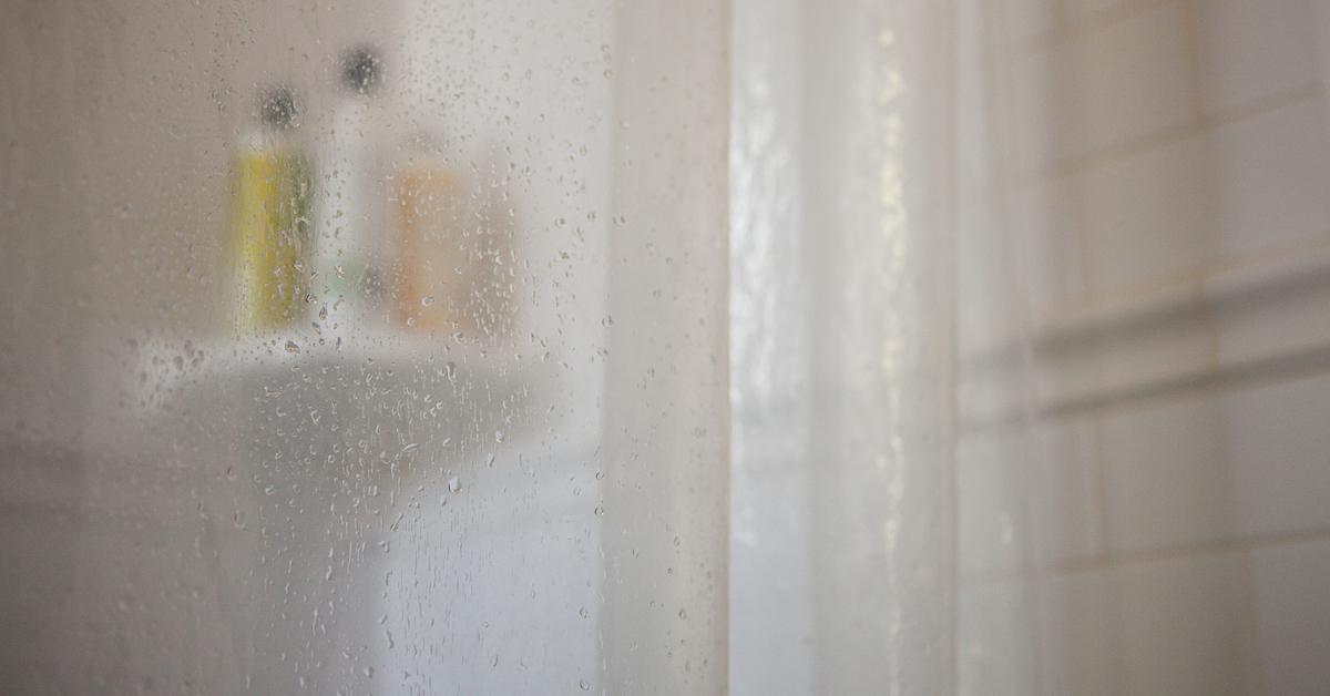 A wet shower certain is pulled in front of bottles. 