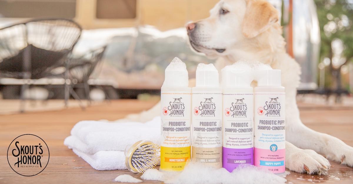 White retriever dog sits on floor next to bottles of Skout's Honor products