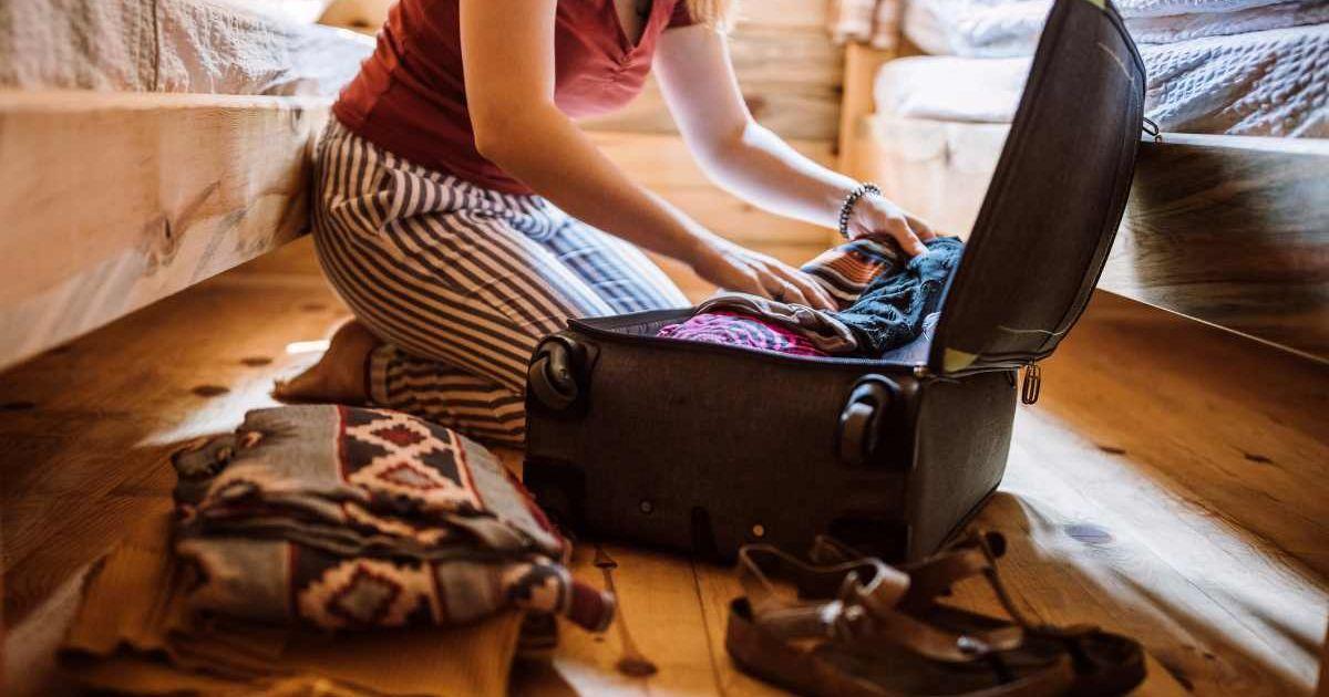 A woman unpacking her luggage sitting on the floor. (Representative Cover Image Source: Getty Images | Pekic)