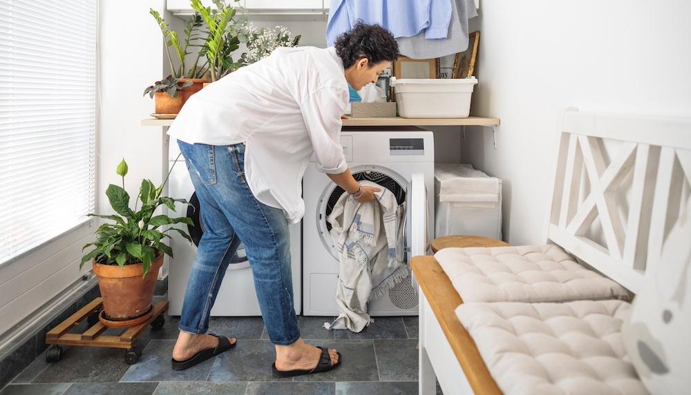 A person putting clothes into a dryer. 