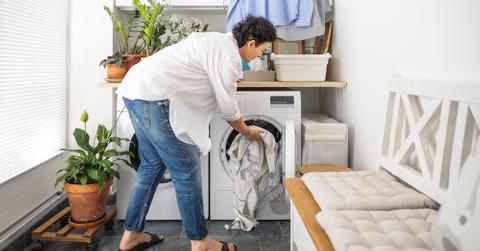 A person putting clothes into a dryer.