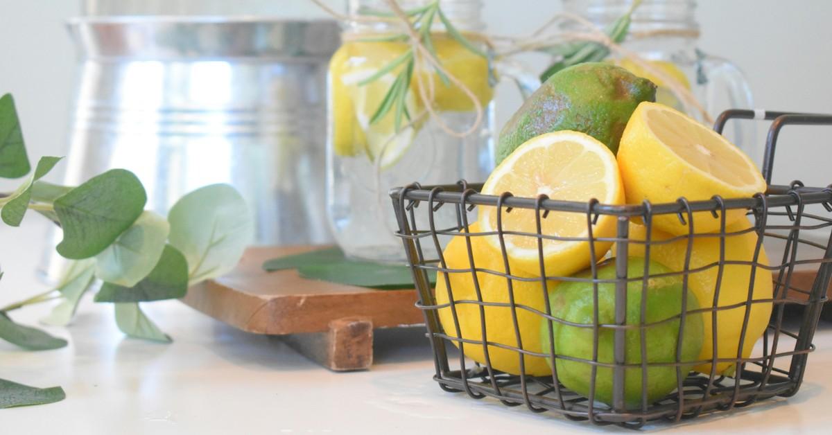 A basket of cut lemons and limes sit next to water