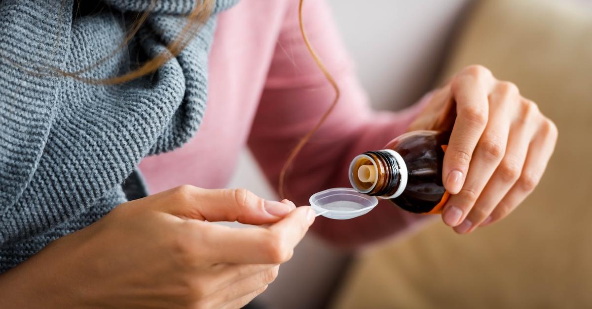 Person measuring out cough syrup