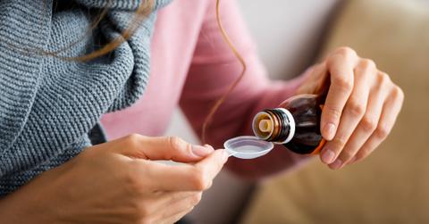 Person measuring out cough syrup