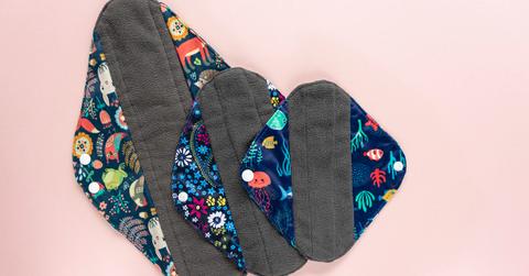 Three reusable menstrual pads on a pink background