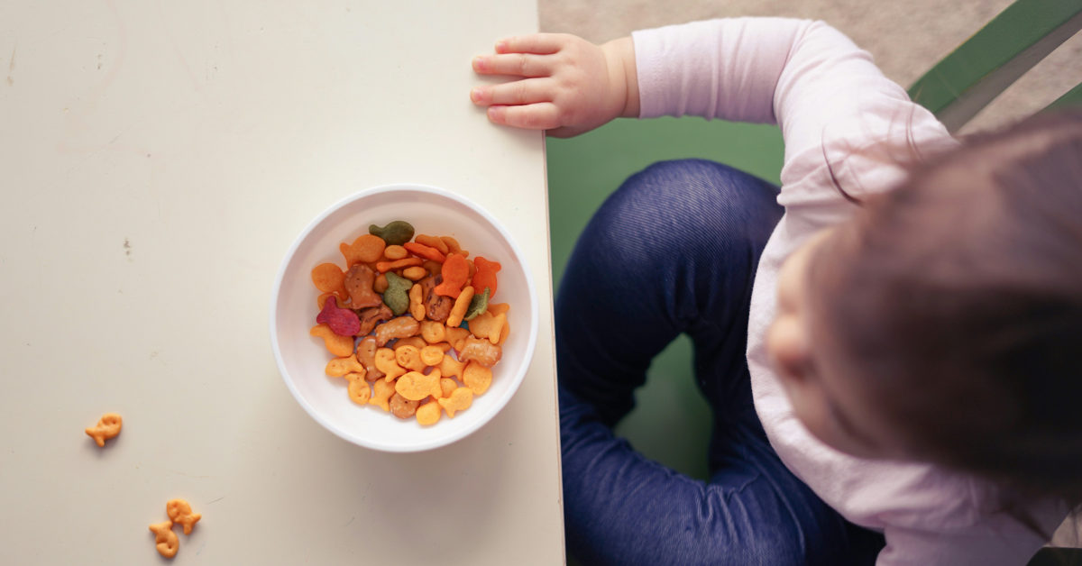 An overhead view of a toddler's bowl of popular snacks