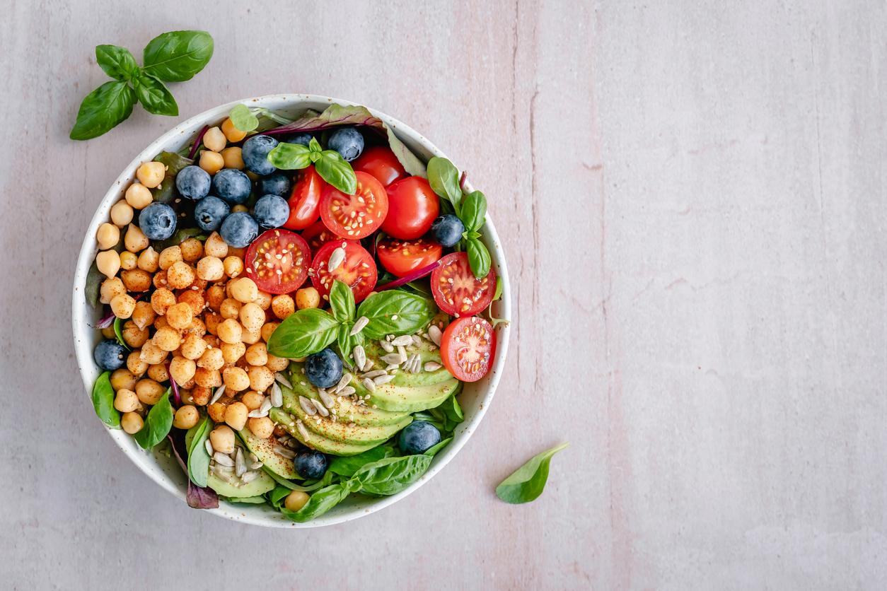 Overhead view of a salad with blueberries, chickpeas, cherry tomatoes, avocado, greens, and more.