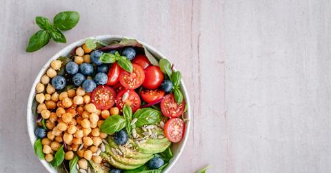 Overhead view of a salad with blueberries, chickpeas, cherry tomatoes, avocado, greens, and more.