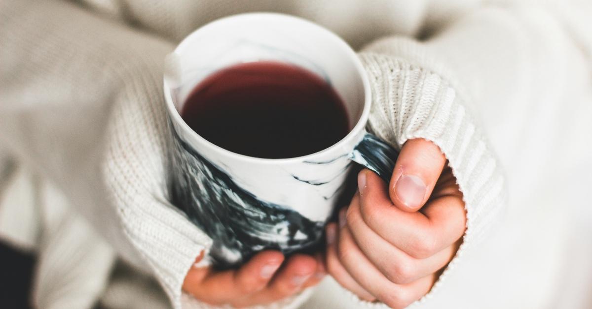 Person holding mug of pink tea. 