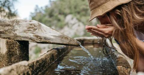 A woman drinking water from an old-fashioned pipe. (Representative Cover Image Source: Pexels | Pavel Danilyuk)