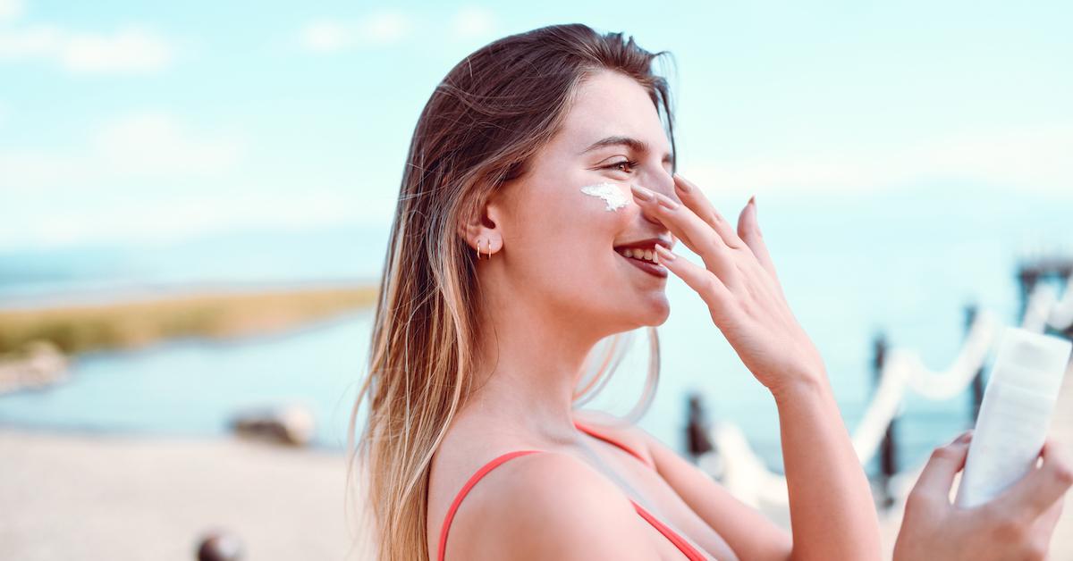 Woman putting sunscreen on face on a beach